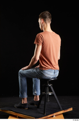 Alessandro Katz  black shoes blue jeans brown t shirt casual dressed sitting whole body  jpg